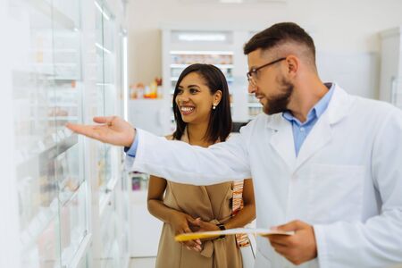 Express positivity. Professional chemist standing in semi position and pointing at shelves with pillsの写真素材