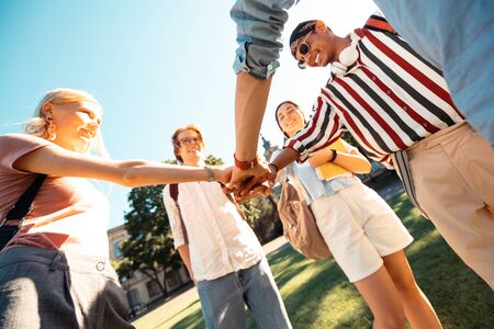 Glad to be in one group. Happy groupmates putting their hands tohether showing each other the...