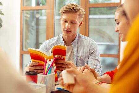 Pleasant thoughts. Handsome man expressing positivity while reading interesting book
