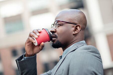 Thinking and drinking. Serious African-American businessman thinking and drinking coffee in the morningの写真素材