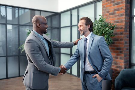 Investor smiling. African-American investor smiling while meeting his business partnerの写真素材