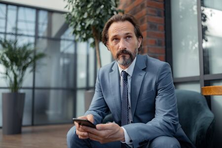 Businessman feeling thoughtful. Handsome prosperous businessman feeling thoughtful while waiting for the meetingの写真素材