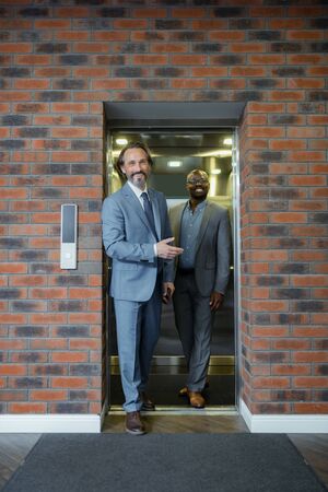 Leaving elevator. Two businessmen leaving elevator smiling before important negotiation with partnersの写真素材