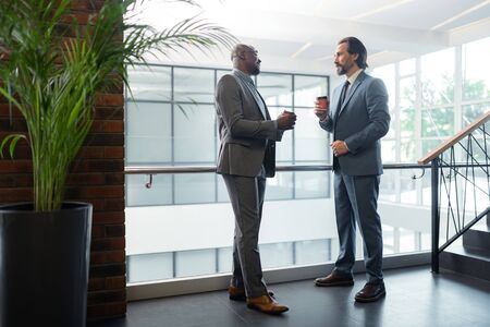 Morning coffee. Dark-skinned businessman drinking coffee with his business partner before having...
