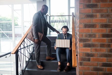 Calming down colleague. Friendly pleasant dark-skinned man calming down his colleague after...