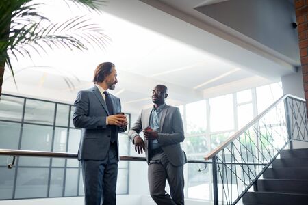 Having coffee time. Bearded businessman speaking with partner and having coffee time in the morning
