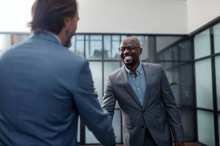 Businessman smiling. Cheerful dark-skinned businessman smiling while talking to colleagueの写真素材