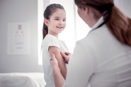 Blood test. Pleasant nice woman putting a plaster on a girls hand after taking her blood for analysisの写真素材