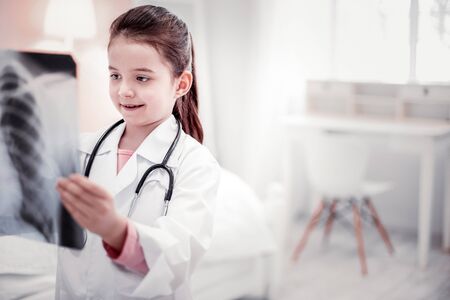 Best therapist. Cute cheerful girl standing with an Xray photo while looking at itの写真素材