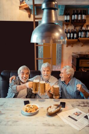 Beer after victory. Cheerful pensioners drinking beer after victory of their football team