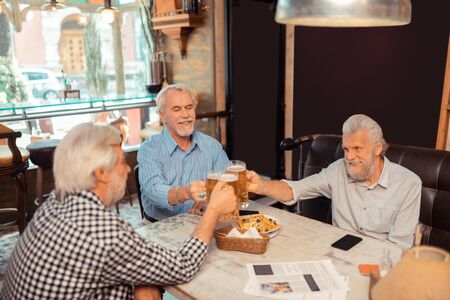 Day of friendship. Retired men celebrating the day of friendship while drinking beer in the pub