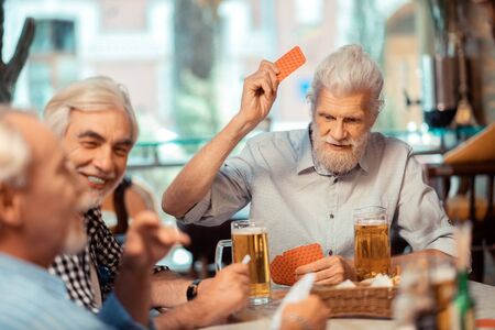 Men gambling. Grey-haired retired men gambling while drinking beer in the pubの写真素材