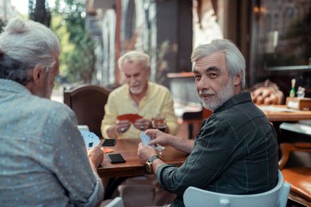 Aged men gambling. Aged retired grey-haired men gambling sitting outside the pubの写真素材