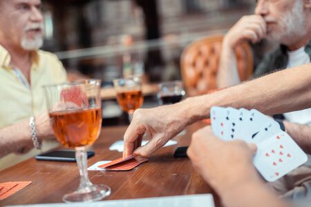Gambling and talking. Close up of bearded grey-haired men gambling and talking