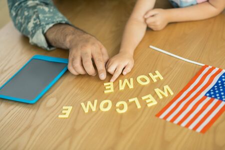 Flag and tablet. Close up of military officer and daughter sitting at the table with flag and tablet
