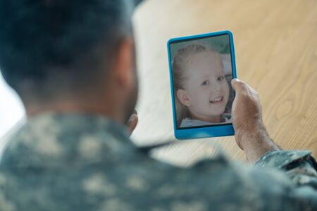 Chat with daughter. Close up of serviceman holding tablet while having video chat withの写真素材