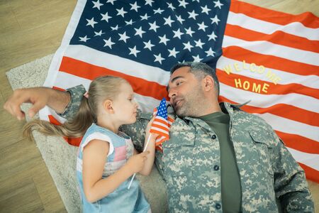 Talking to daughter. Happy heroic military servant feeling touching talking to his little daughter