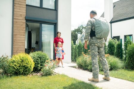 Uniform and backpack. Military man wearing uniform and backpack coming back home to wife and daughterの写真素材