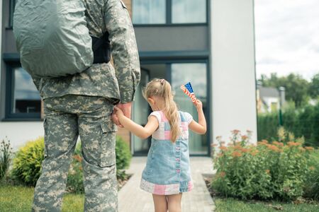 Hand of father. Cute girl wearing summer dress holding hand of her father serving in armed forcesの写真素材