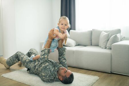 Playing with daddy. Little cute daughter feeling amazing finally playing with daddy after military serviceの写真素材