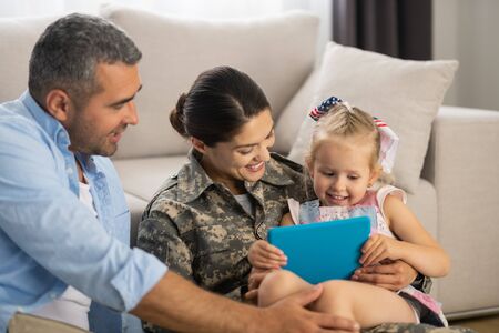Unbelievably happy. Military woman feeling unbelievably happy watching cartoon with daughter and husbandの写真素材