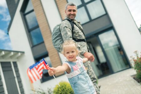 Coming home. Military man feeling extremely happy while coming home holding hand of his lovely girlの写真素材