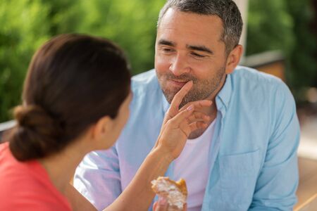 Caring wife. Dark-haired wife taking care of husband while feeding him with yummy croissantの写真素材