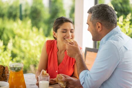 Sharing his croissant. caring husband sharing his croissant with his wife while enjoying breakfast togetherの写真素材