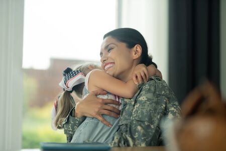 Hugging lovely daughter. Beautiful military woman laughing while hugging her lovely daughterの写真素材