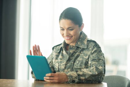 Chat with family. Beautiful woman serving in armed forces having video chat with family on tabletの写真素材