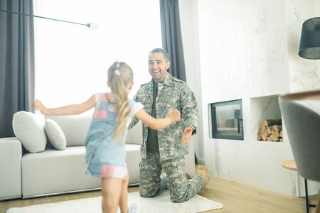 Running to father. Blonde little daughter running to father coming back home after military serviceの写真素材