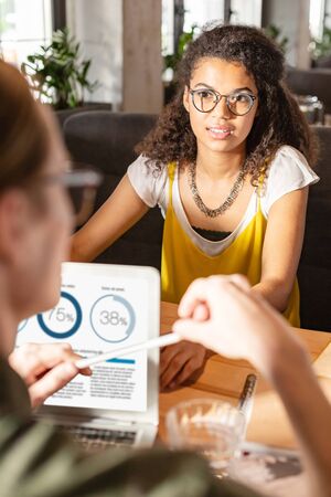 Comprehending the information. Nice serious woman listening to her colleague while comprehending the...