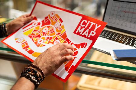 City map. Hands of a tourist wearing shambala bracelets holding a city map looking for the best way to stroll.の写真素材