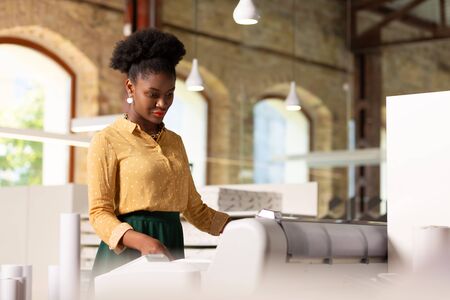 Publishing agency. Beautiful stylish worker of publishing agency using printer while working