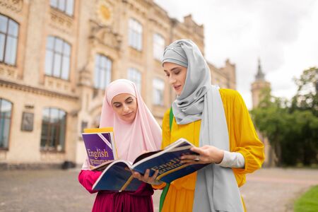 Worried before exam. International muslim students feeling worried before exam while reading booksの写真素材