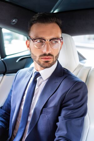 Handsome businessman. Handsome young bearded businessman wearing dark suit sitting in the carの写真素材