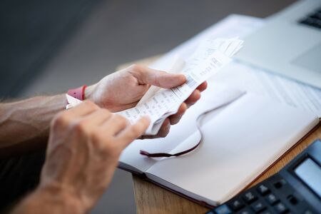 Businessman holding bills. Close up of busy young businessman holding bills while studying expensesの写真素材