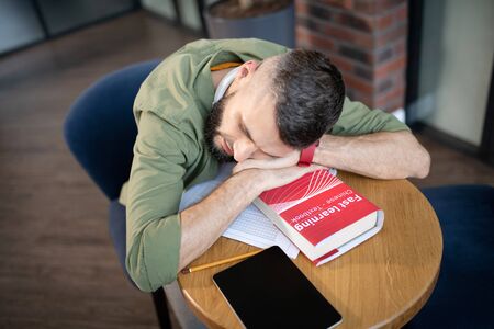 Sleeping on book. Top view of exhausted student sleeping on book lying near table on the table