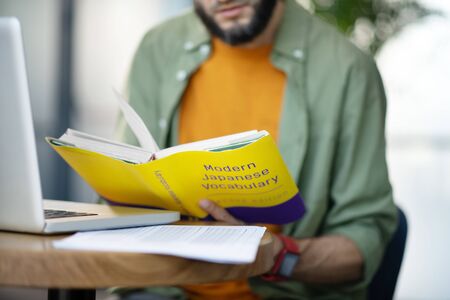 Study foreign languages. Smart young businessman studying foreign languages sitting at the table