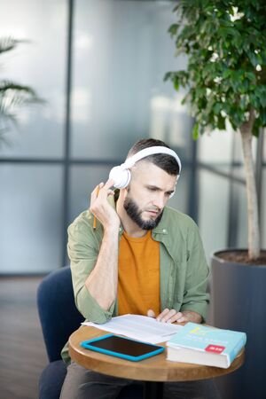 Test time. Stylish bearded student getting master degree wearing earphones while preparing for test