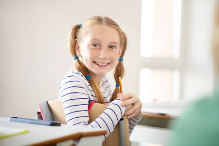 Girl with freckles. Cute girl with freckles smiling broadly while feeling good at the lesson
