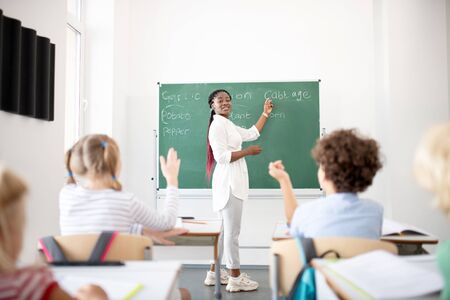Children raising hands. Active children raising hands while knowing the answer for question of...