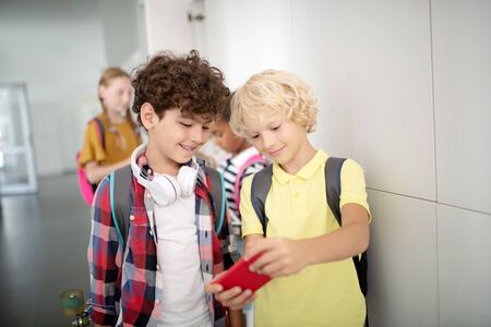 Favorite video game. Blonde-haired boy showing his favorite video game to best friend while having...