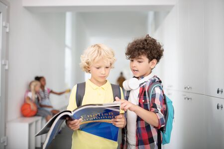 Repeating English grammar. Two boys holding book and repeating English grammar before lesson starts