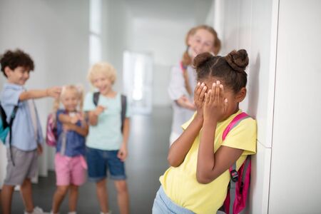 Girl closing face. Dark-skinned girl closing her face while suffering from bullying and feeling...