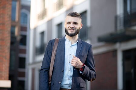 Walking to office. Handsome young dark-haired man wearing smart watch walking to the officeの写真素材
