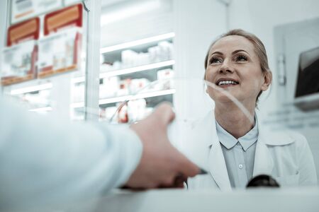 Handing the medicine. A customer handing the medicine to the smiling beautiful pharmacist at the checkoutの写真素材