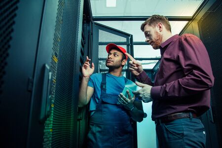 Having a problem. Nice smart people standing together near the server while having a problem with itの写真素材