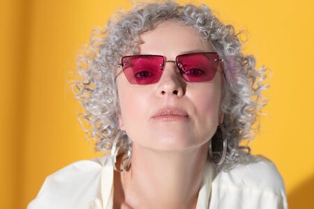 Pink glasses. Close up of curly grey-haired beautiful woman wearing pink glassesの写真素材