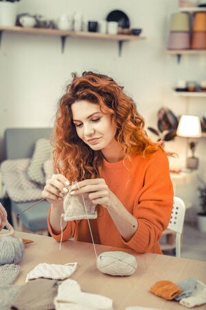 Working process. Attractive handywoman keeping smile on her face while testing wool yarnの写真素材